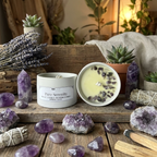 Candle labeled 'Pure Serenity' surrounded by crystals, lavender, and plants on a wooden surface.