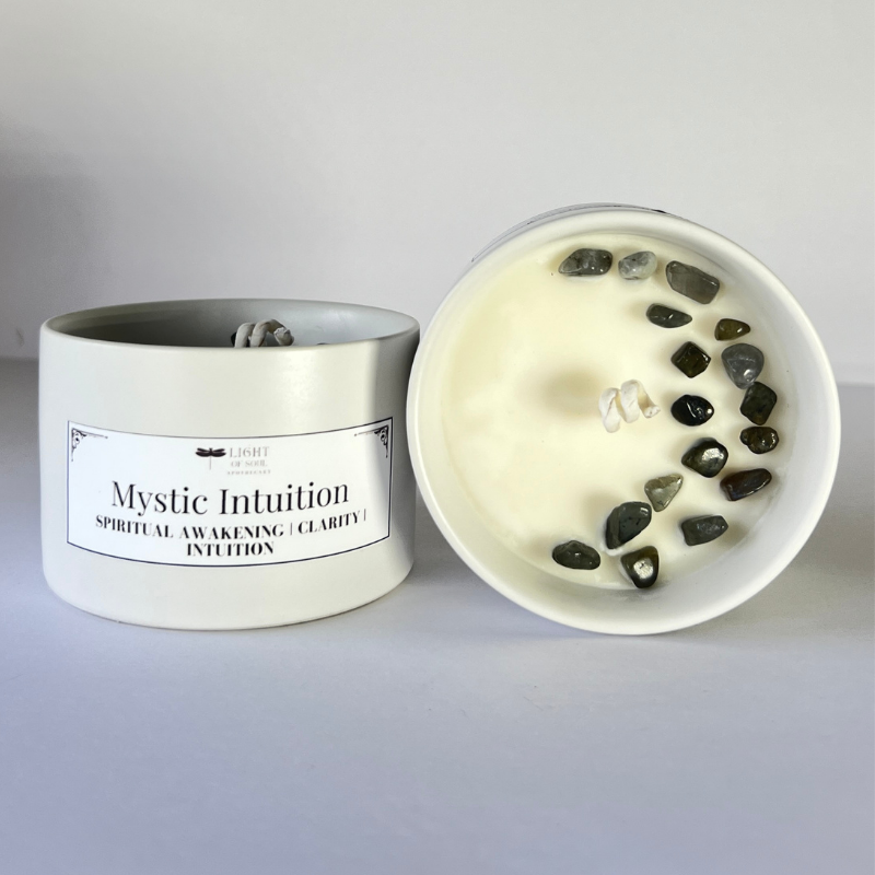 Candle with labradorite stones inside labeled 'Mystic Intuition' on a gray background