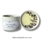 Candle with decorative stones in a white container labeled 'Pure Serenity' from Lightsoulapothecarry.com.